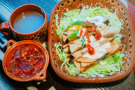 A Mexican flautas with lettuce, avocado, cream, sauce and fresh waterの写真素材