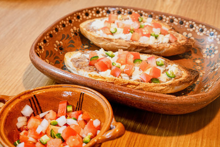 A Mexican Molletes, traditional food with bread, beans, cheese, tomato and chiliの写真素材