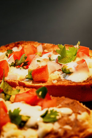 A Mexican Molletes, traditional food with bread, beans, cheese, tomato and chiliの写真素材