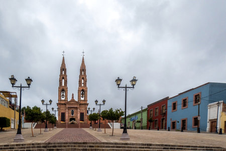 Explore the Santuario de Guadalupe in San Luis de la Paz, Guanajuato. Admire its symmetrical beauty, towering spire, and serene chapel within a historic town squareの写真素材
