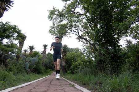 A man finds exhilarating joy while running through diverse landscapes - roads, paths, and forests - amidst trees, grass, and skyの写真素材