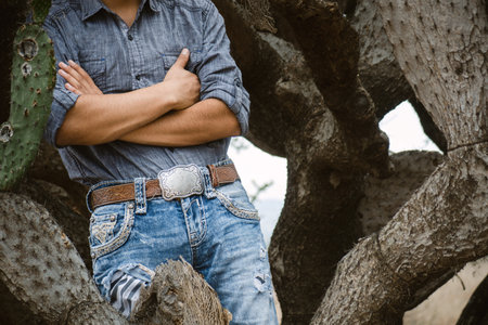 A cowboy in jeans, sitting on a rock in the forest, with bare feet and a joyful spiritの写真素材