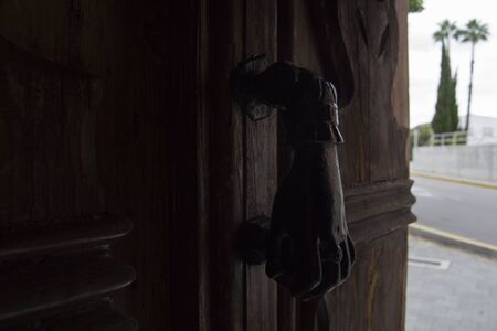 Iron hand door knocker on old wooden door.の写真素材