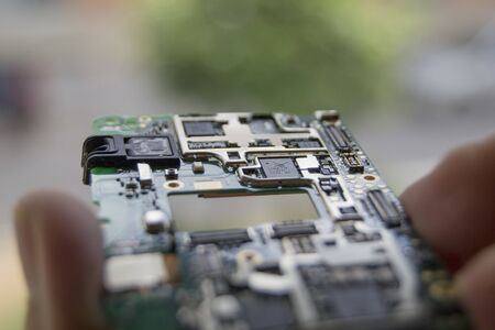 Mobile phone circuit on a hand with an unfocused backgroundの写真素材