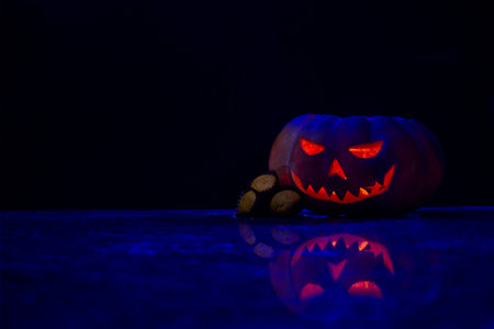Halloween pumpkin with three pumpkin muffins resting on top of them, all on a dark background.