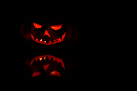 Hallowen pumpkin face glowing in the dark with reflection.