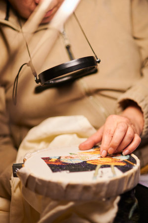 Woman hands doing cross-stitch. A close up of embroidery.