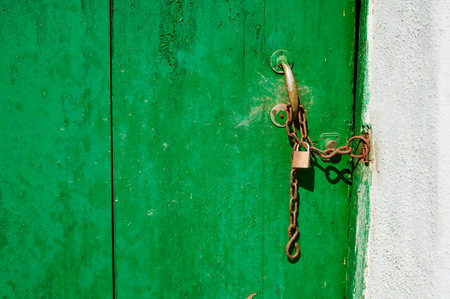 Old wooden door green with padlock and chain