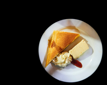 Dessert plate with ice cream, cream and cheesecake on black background