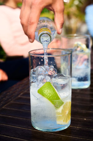 Detail of barkeeper serving a gin tonic in a terrace