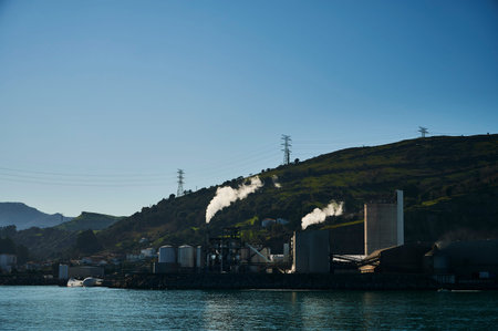 Two chimneys emitting white smoke at dawn on the seashore