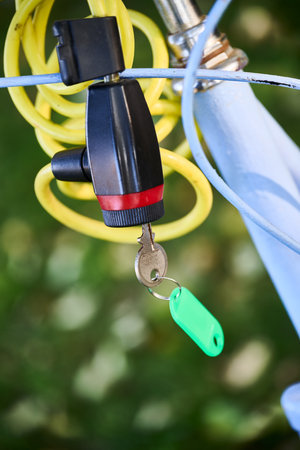 Anti-theft chain lock with yellow cable securing a white bicycleの写真素材
