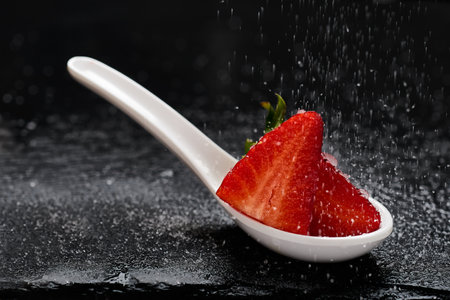 Strawberries over white spoon and sugar fallingの写真素材