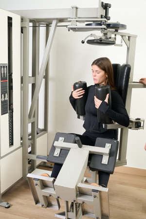 Young woman performing a core workout on specialized gym equipment. Focusing on fitness development...