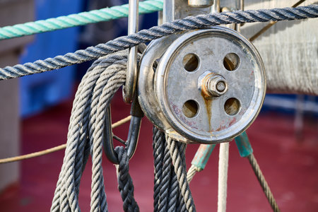 Pulley and nautical ropes providing essential mechanical support, showing wear from marine...