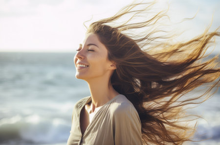 Young woman with eyes closed enjoying her freedom by the sea coastの素材