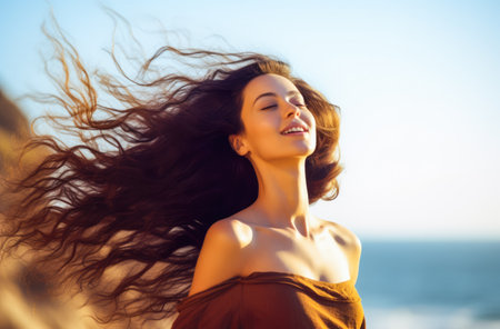 Young woman with eyes closed enjoying her freedom by the sea coastの素材