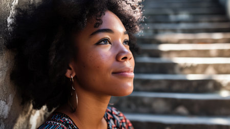 Young dark skinned woman sitting on stairs taking a brakeの素材
