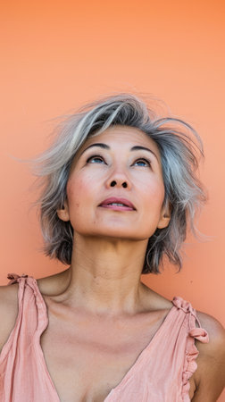 Close up of a middle aged woman with a peach copyspace backgroundの素材