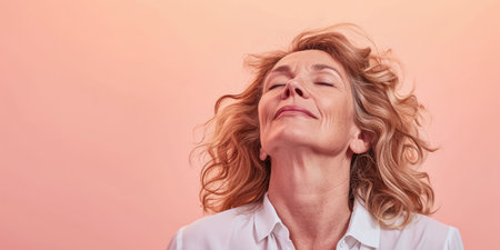 Close up of a confident middle aged woman with a peach copyspace backgroundの素材