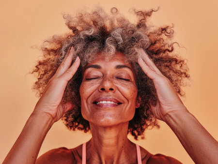 Close up of a confident middle aged woman with a peach copyspace backgroundの素材