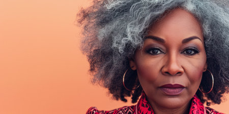 Close up of a confident middle aged woman with a peach copyspace backgroundの素材