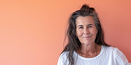 Close up of a confident middle aged woman with a peach copyspace backgroundの素材