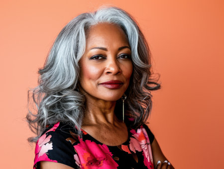 Close up of a confident middle aged woman with a peach copyspace backgroundの素材