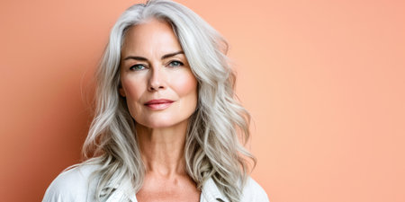 Close up of a confident middle aged woman with a peach copyspace backgroundの素材