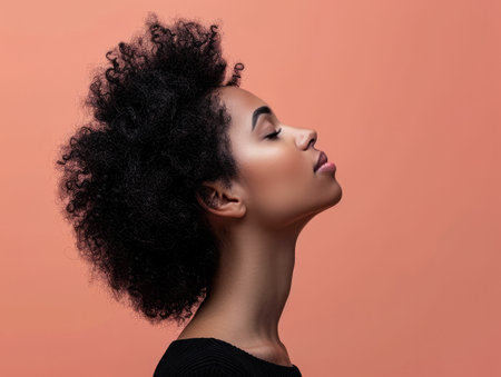 Close up of a confident young woman with a peach copyspace background for textの素材