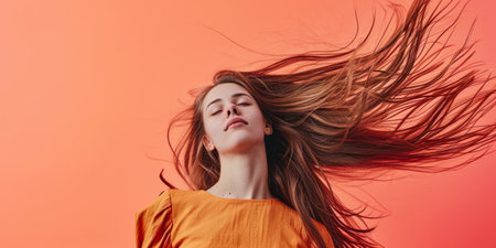 Close up of a confident young woman with a peach copyspace background for textの素材