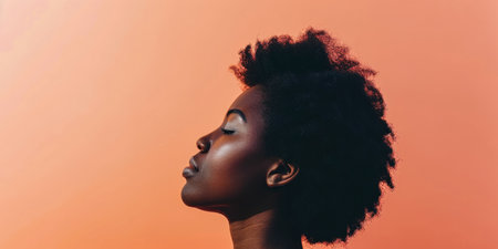 Close up of a confident young woman with a peach copyspace background for textの素材