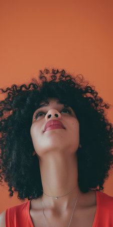 Close up of a confident young woman with a peach copyspace background for textの素材