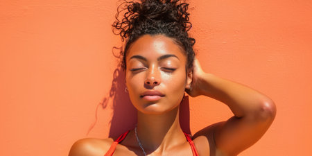 Close up of a confident young woman with a peach copyspace background for textの素材