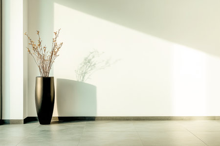 A tall black vase holds a delicate arrangement of dried flowers, which casts intricate shadows on a bright, freshly painted wall in a modern room. Sunlight enhances the serene atmosphere.の素材