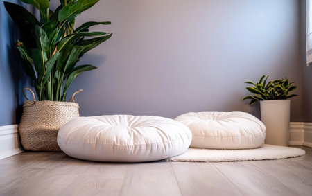 A calming space features two round white cushions on a soft rug, surrounded by vibrant indoor plants. The light gray wall adds to the peaceful atmosphere.の素材