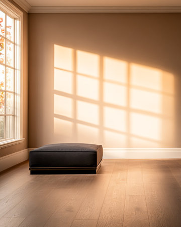 Soft light streams through a large window, illuminating a simple room with a black cushion resting on a warm wooden floor, creating a tranquil atmosphere.の素材