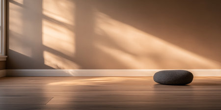 Sunlight pours into a calm corner of the room, casting soft shadows on the wooden floor and highlighting a smooth stone placed in quiet elegance.の素材
