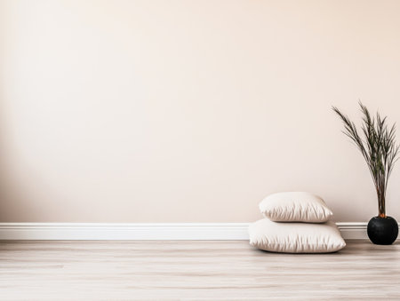 A serene and minimalistic room showcases two plush pillows on a wooden floor beside a stylish potted plant against a calm beige wall. Sunlight enhances the space's inviting ambiance.の素材
