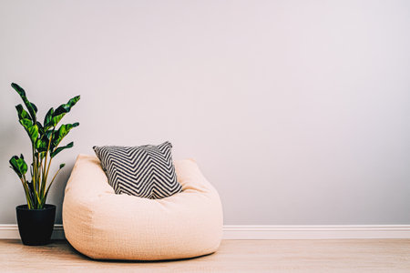 A spacious living area features a soft bean bag chair adorned with a striped pillow, next to a stylish green plant, all set against a soothing gray wall.の素材