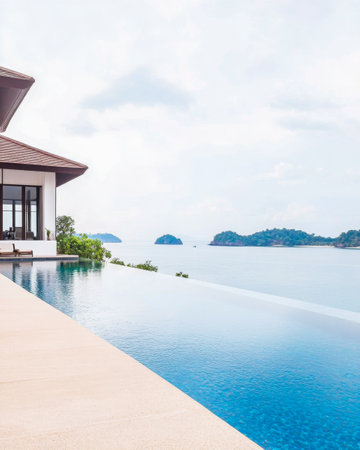 A luxurious villa features a stunning infinity pool that seamlessly blends with the ocean, offering breathtaking views of distant islands under a soft, overcast sky.の素材