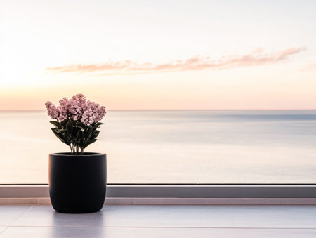 A black pot holds vibrant pink flowers, positioned by a large glass window showcasing a calm seascape at sunset, creating a peaceful atmosphere.の素材