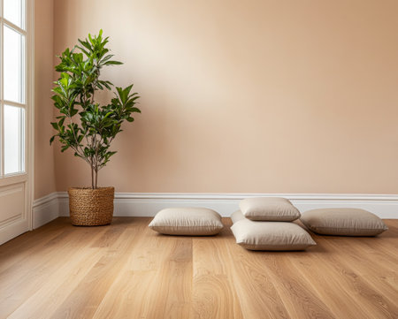 A calm indoor area features neutral-colored walls and wooden flooring, adorned with four soft pillows and a leafy potted plant, inviting relaxation and comfort in the sunlight.の素材