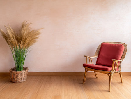 A warm and inviting corner showcases a wicker chair with red cushions beside a pot of pampas grass against a soft, neutral wall, creating a serene atmosphere.の素材
