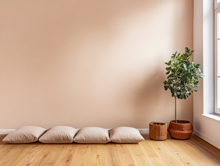 A warm, inviting living area features soft floor cushions along a light wooden floor, complemented by a leafy indoor plant near a window, enhancing the minimalist aesthetic of the space.の素材