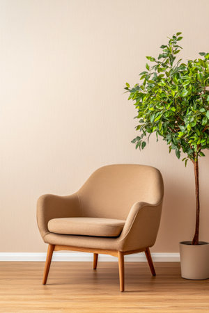 A beige chair is positioned next to a leafy green plant in a pot, creating a stylish and inviting atmosphere in a modern living area with softly lit walls.の素材