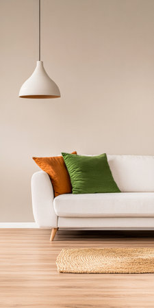 A contemporary living room features a white sofa adorned with green and orange pillows, complemented by a warm pendant lamp. The wooden floor and woven rug enhance the inviting atmosphere.の素材