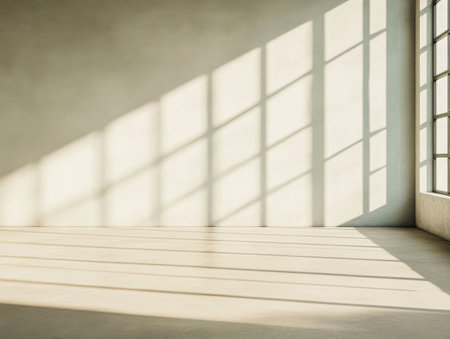 Bright sunlight filters through large windows, creating intricate shadows on the smooth floor and walls. The minimalist design contributes to a peaceful and airy atmosphere in the room.の素材