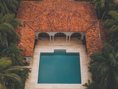 This villa features a stunning pool and a terracotta-tiled roof nestled among tall palm trees in a serene environment, perfect for relaxation and outdoor enjoyment.の素材