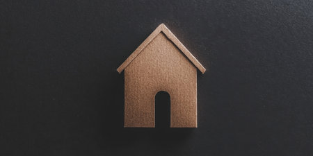 A small wooden house model is placed on a dark surface, showcasing a minimalist design that represents the concept of home and comfort in modern decor.の素材